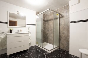 A modern bathroom with a glass-enclosed shower, white vanity with drawers, a mirror, and a potted plant. - Apartment with 3 bedrooms and 2 bathrooms on the beachfront (Alcúdia)