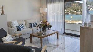 A modern living room with a sofa, armchairs, a coffee table, and a view of a beach through large windows. - PLAYA VISTA MAR DUPLEX APARTMENT (El Port de la Selva)