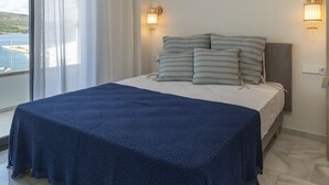 A bedroom with a large bed, a view of the sea, and two wall-mounted lights. - PLAYA VISTA MAR DUPLEX APARTMENT (El Port de la Selva)