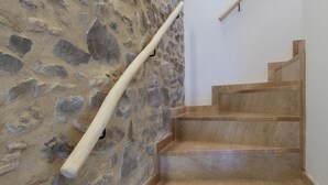 A staircase with a stone wall on one side and a wooden handrail. - PLAYA VISTA MAR DUPLEX APARTMENT (El Port de la Selva)
