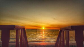 A sunset over a calm sea with wooden benches facing the horizon. - Delta Blu Residence Village - Villetta Trilocale 06 (Lido di Pomposa)