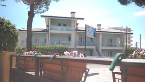 Um hotel com vários andares, varandas, uma placa de identificação e arranjos florais.