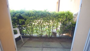 Uma varanda com um pequeno muro, uma cadeira branca e piso de concreto.