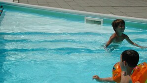 Piscina com água azul cristalina e deck revestido com azulejos.
