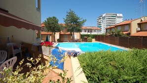 A swimming pool surrounded by a patio area with outdoor furniture and a small garden. - Delta Blu Residence Village - Appartamento Quadrilocale 2 (Lido di Pomposa)