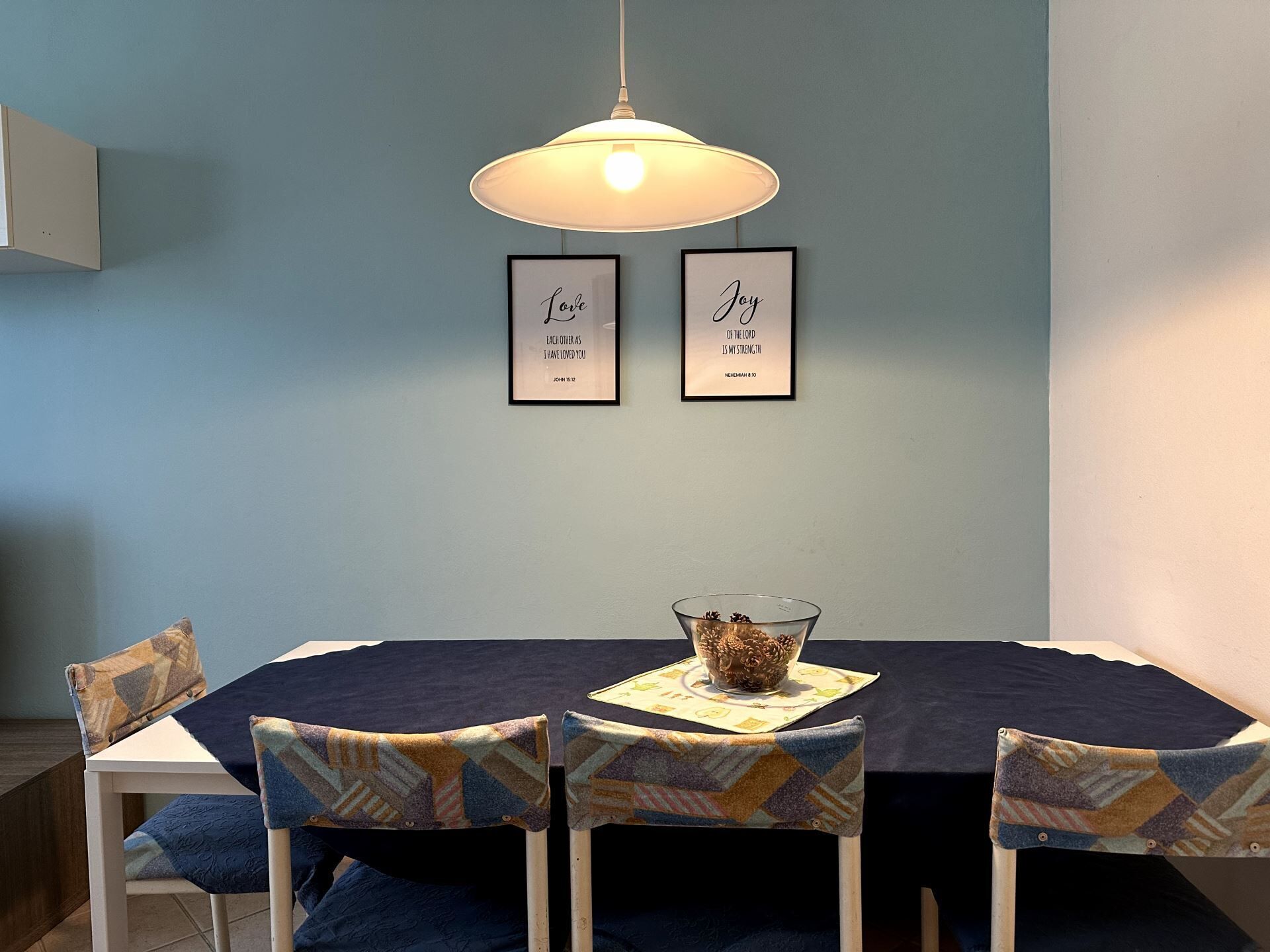 Un coin repas avec une table, des chaises et deux citations encadrées accrochées au mur.