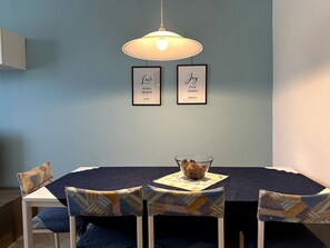 Et spiseområde med et bord, stole og to billeder med citater på væggen.