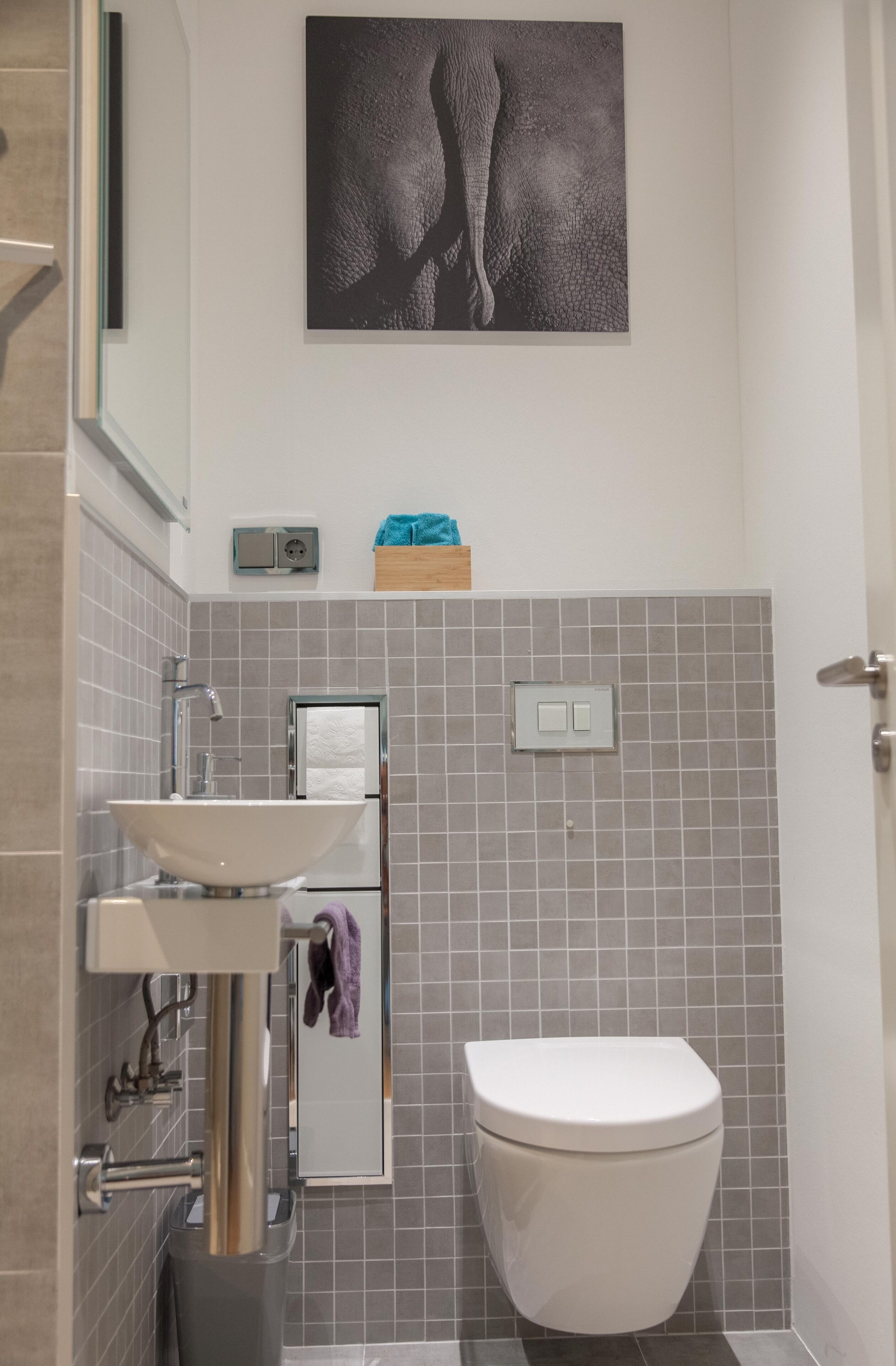Une salle de bain moderne avec un lavabo blanc, des toilettes et un porte-serviettes.