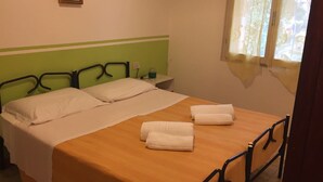 Ein Einzelbett mit Holz Kopfteil und zwei Kissen, ein Nachttisch mit Lampe und zwei Handtücher auf dem Bett.
