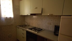 A small kitchen with a gas stove, a sink, and a refrigerator.