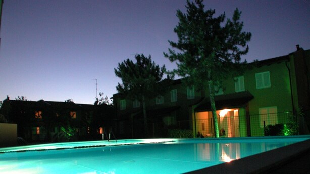 A swimming pool with a view of a building with multiple windows and a tree in the background.