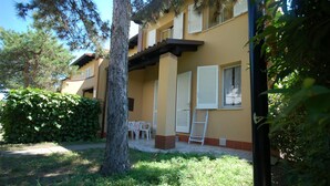 Un bâtiment à la façade jaune, aux volets blancs et doté d’un petit patio avec une table et des chaises.