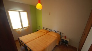 A bedroom with a bed, bedside table, and a hanging lamp. - Delta Blu Residence Village - Villetta Trilocale 19 (Lido di Pomposa)
