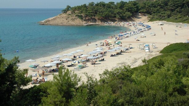 A beach with umbrellas and sun loungers, a sandy shore, and a hilly backdrop. - Tripiti Bungalows (Thasos)