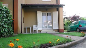 A two-story building with a covered porch, a small table, and a chair. - Delta Blu Residence Village - Villetta Trilocale 22 (Lido di Pomposa)