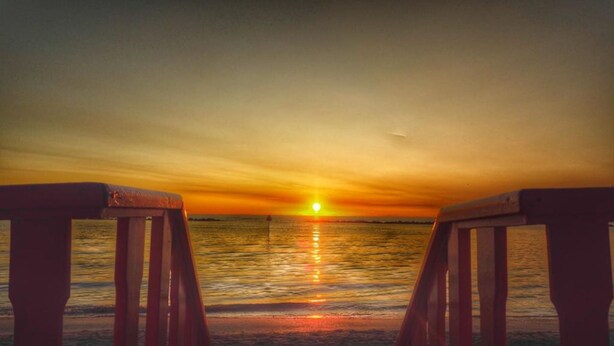 A sunset over a calm sea with wooden benches facing the horizon. - Delta Blu Residence Village - Villetta Trilocale 22 (Lido di Pomposa)