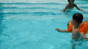 A swimming pool with clear blue water and a tiled deck surrounding it.