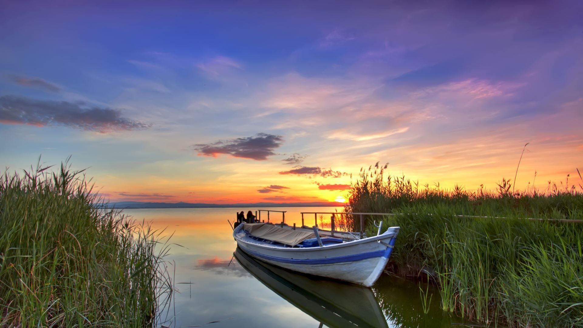 A boat docked at a pier with a sunset in the background.
