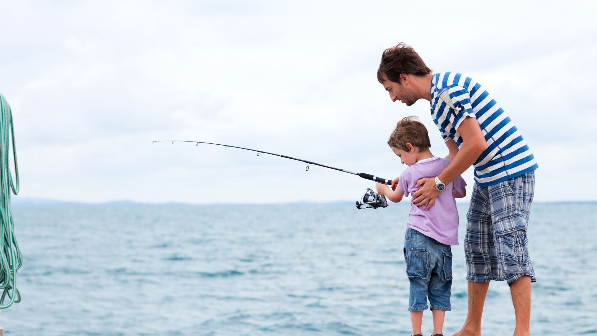 A man and a child fishing by the sea.