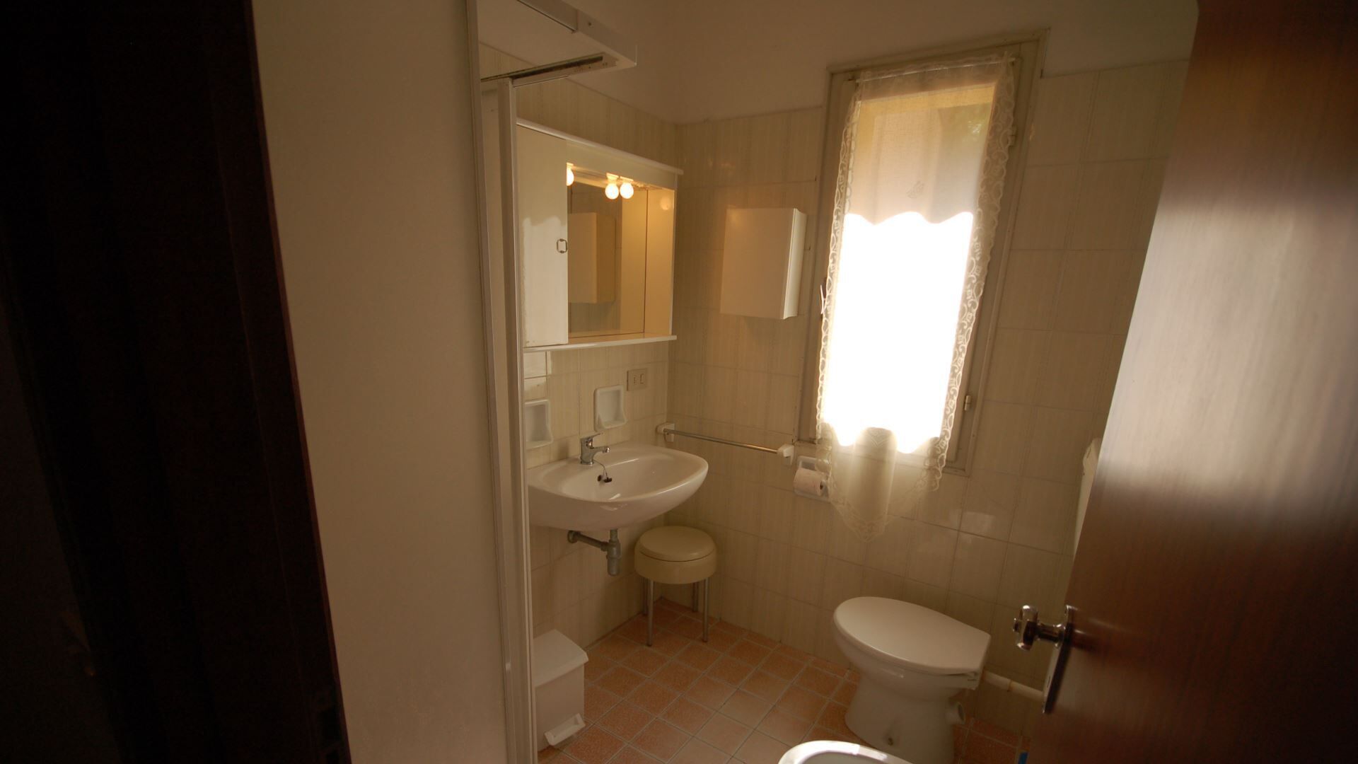 A small, clean bathroom with a toilet, sink, and mirror.