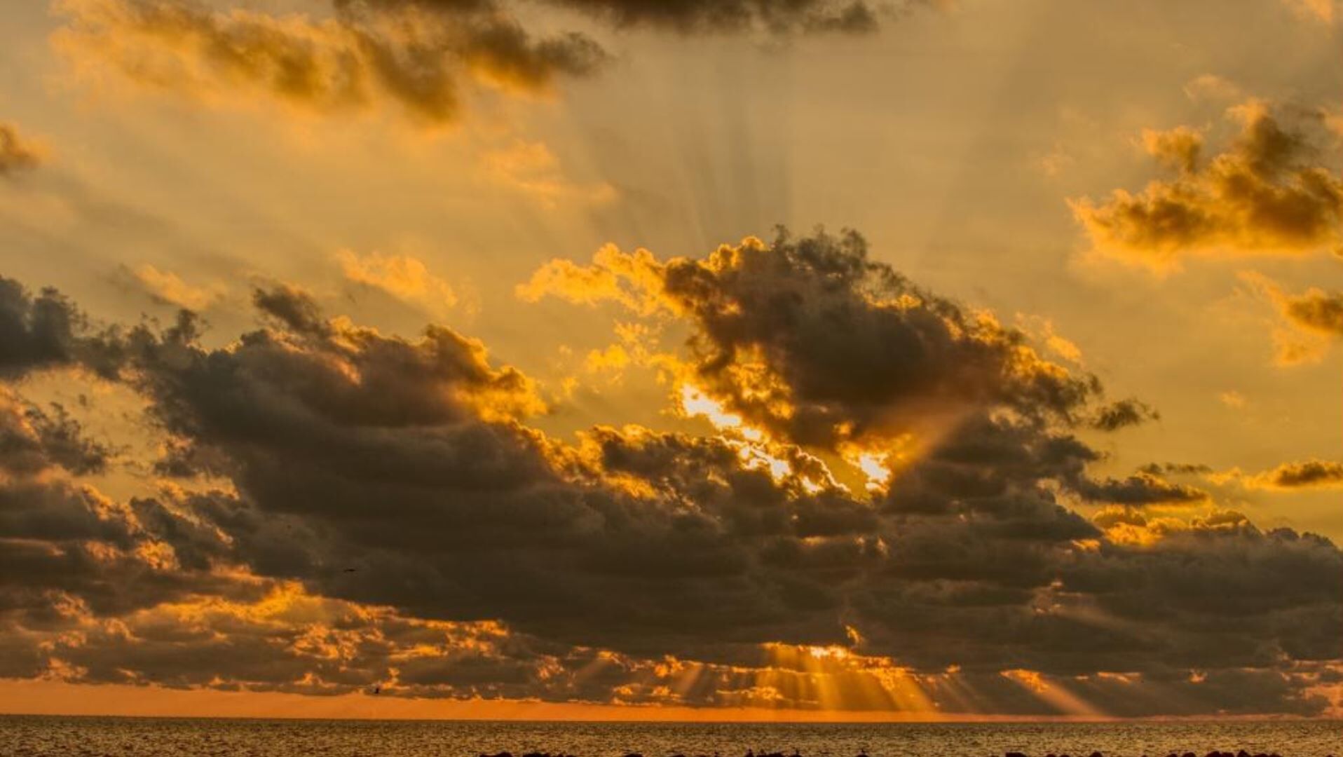 Ein Sonnenuntergang über einem Gewässer mit Wolken.