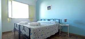 Une chambre à coucher avec un lit, une table de chevet, une lampe et une fenêtre.