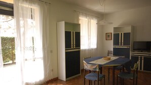 Een eetgedeelte met een tafel, stoelen, een televisie en kastjes.