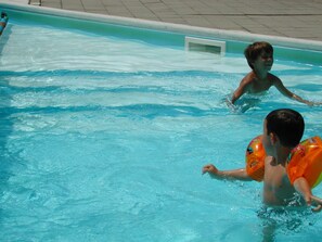 Ein Swimmingpool mit klarem, blauem Wasser und einer ihn umgebenden gefliesten Terrasse.