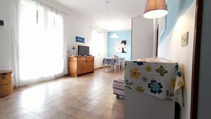 Uma sala de estar ampla com um armário de madeira, uma televisão e uma mesa de jantar com cadeiras.