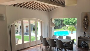 A spacious living area with a dining table and chairs, a glass coffee table, and a view of a swimming pool. - EXCEPTIONAL AND RARE, 15 km from MARSEILLE, BE 3 km FROM AUBAGNE, MAS DE STANDING (Roquevaire)