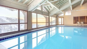 Una piscina interior con grandes ventanales que ofrecen vistas a colinas nevadas.