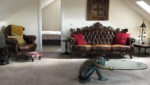 A spacious living room with a high ceiling, a large ornate sofa, a small round table, and a sculpture. - Country Retreat Sleeps 2 Near Cymyran Beach (Holyhead)