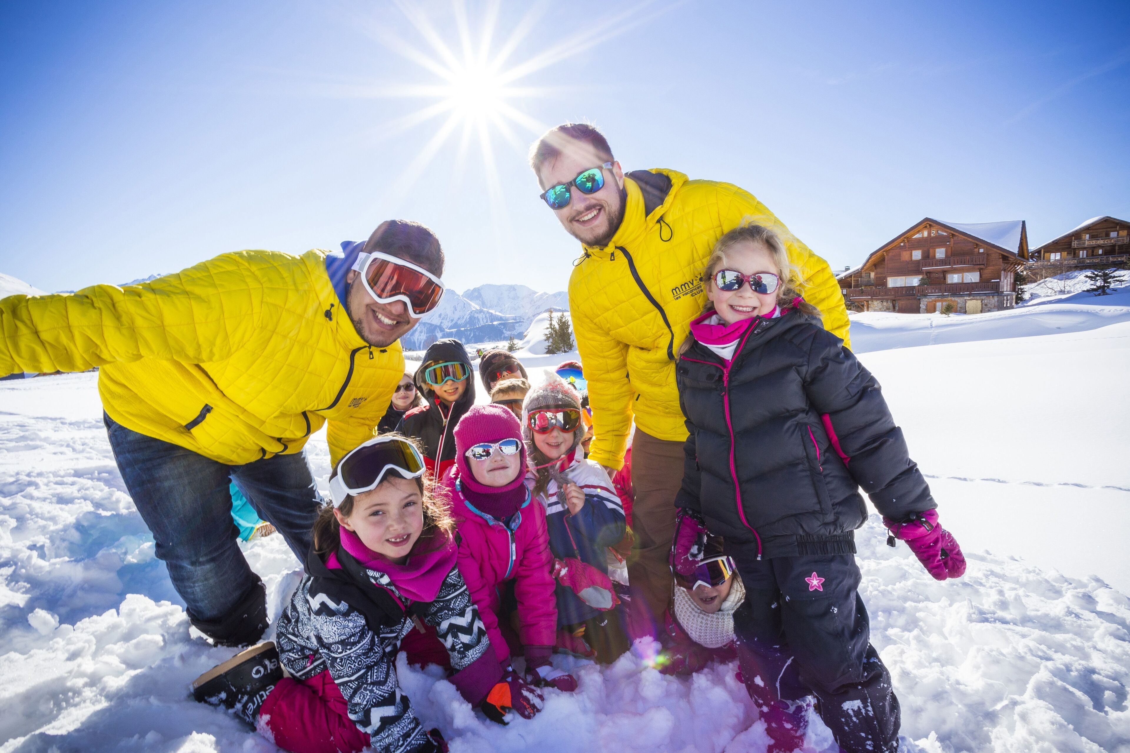 Een groep mensen in een besneeuwd landschap met een heldere lucht en een gebouw op de achtergrond.