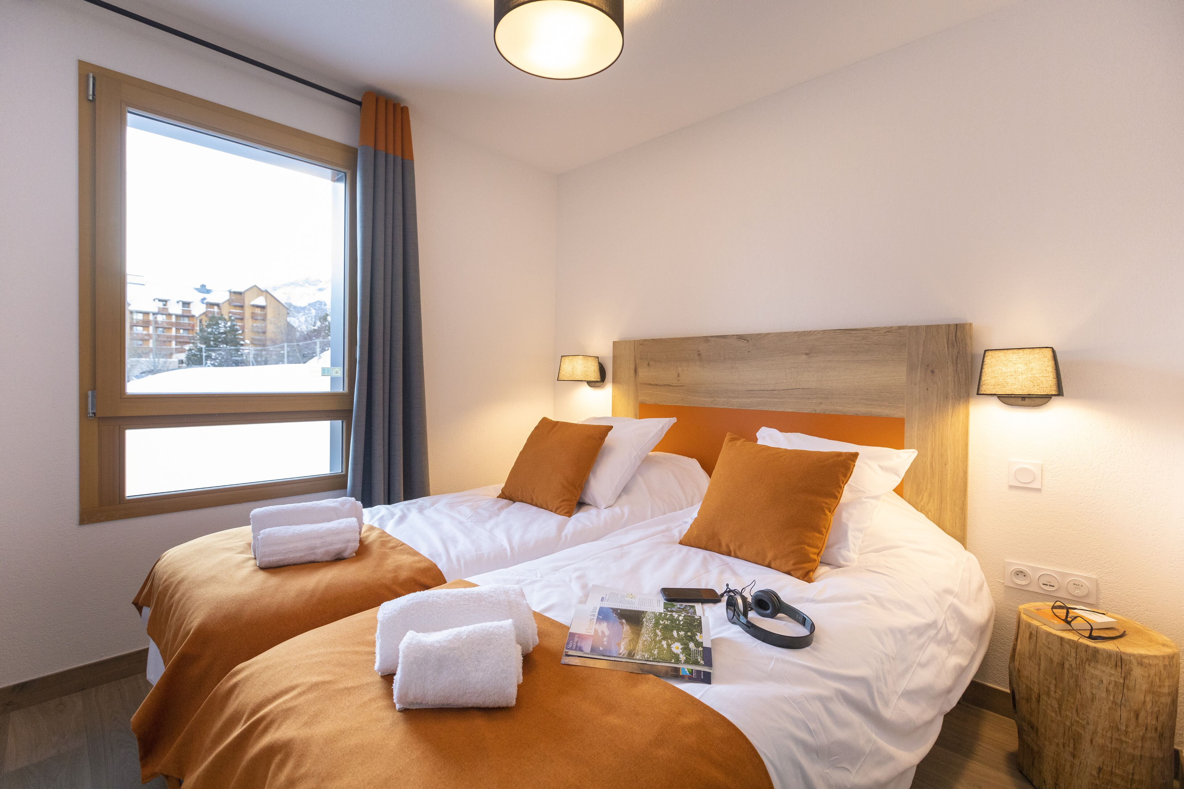 Et hotelværelse med to senge, et stort vindue og udsigt til bygninger.