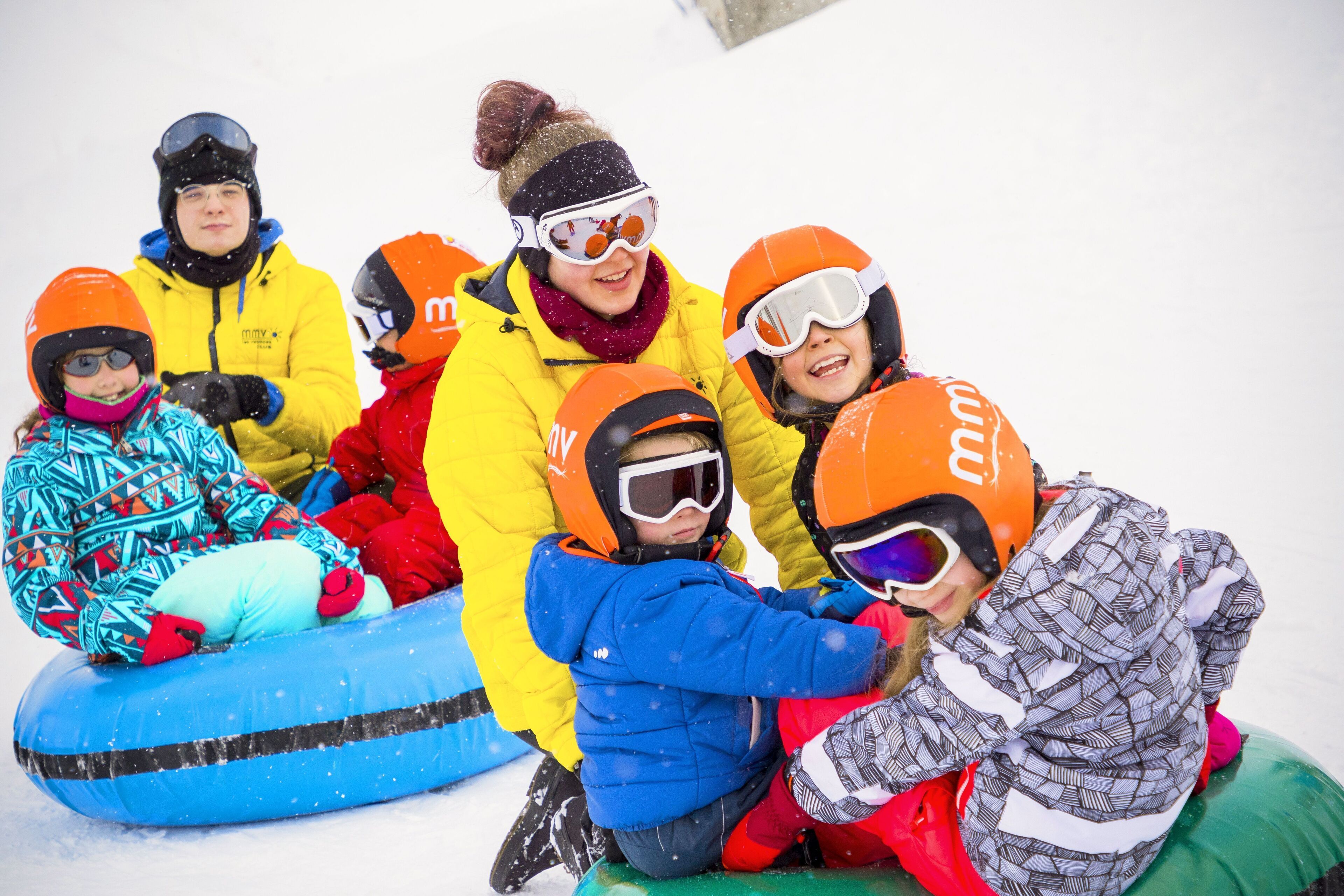 A group of people sitting on a blue inflatable raft in the snow.