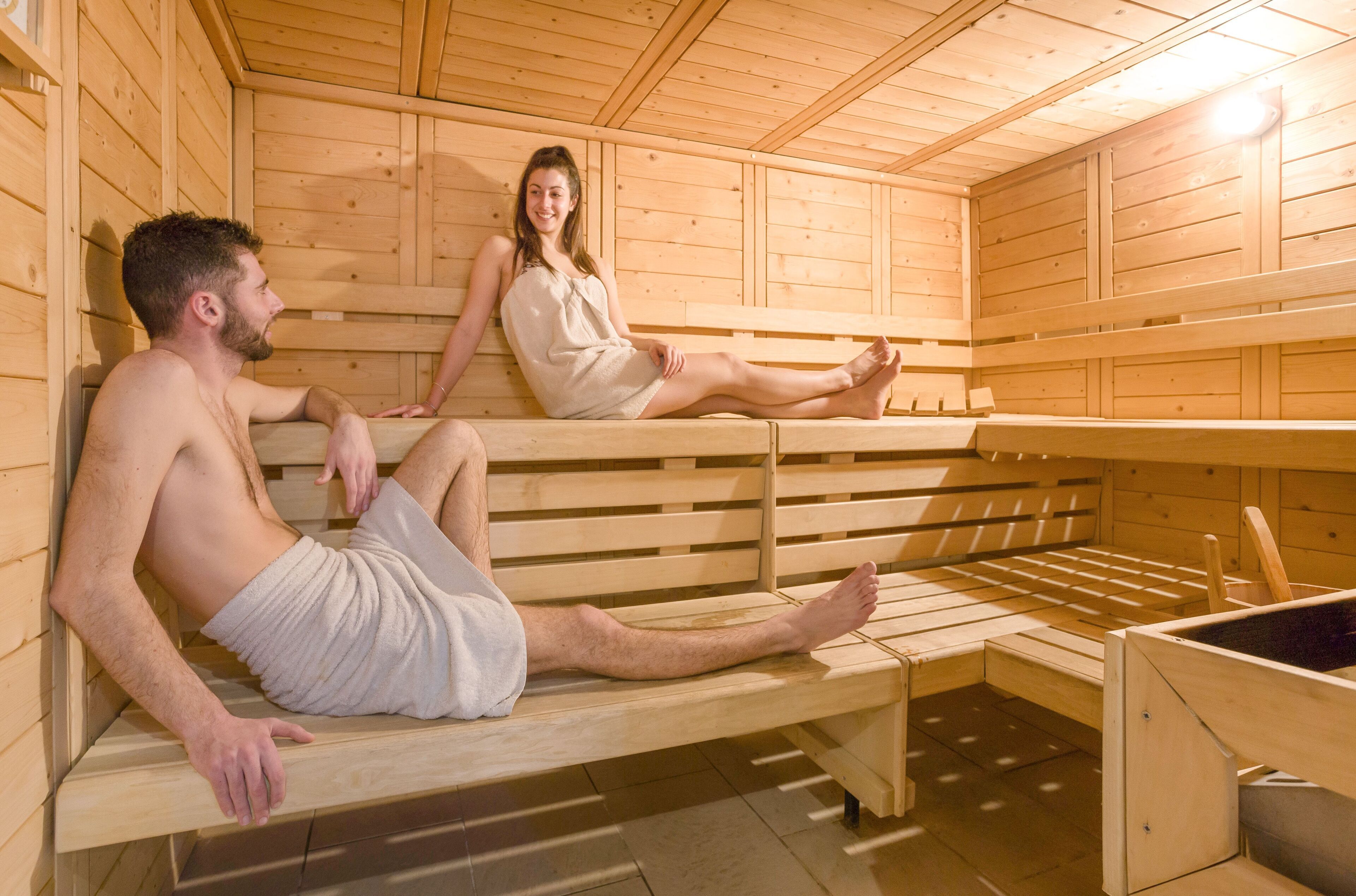A sauna room with wooden benches and benches, and a wooden wall.