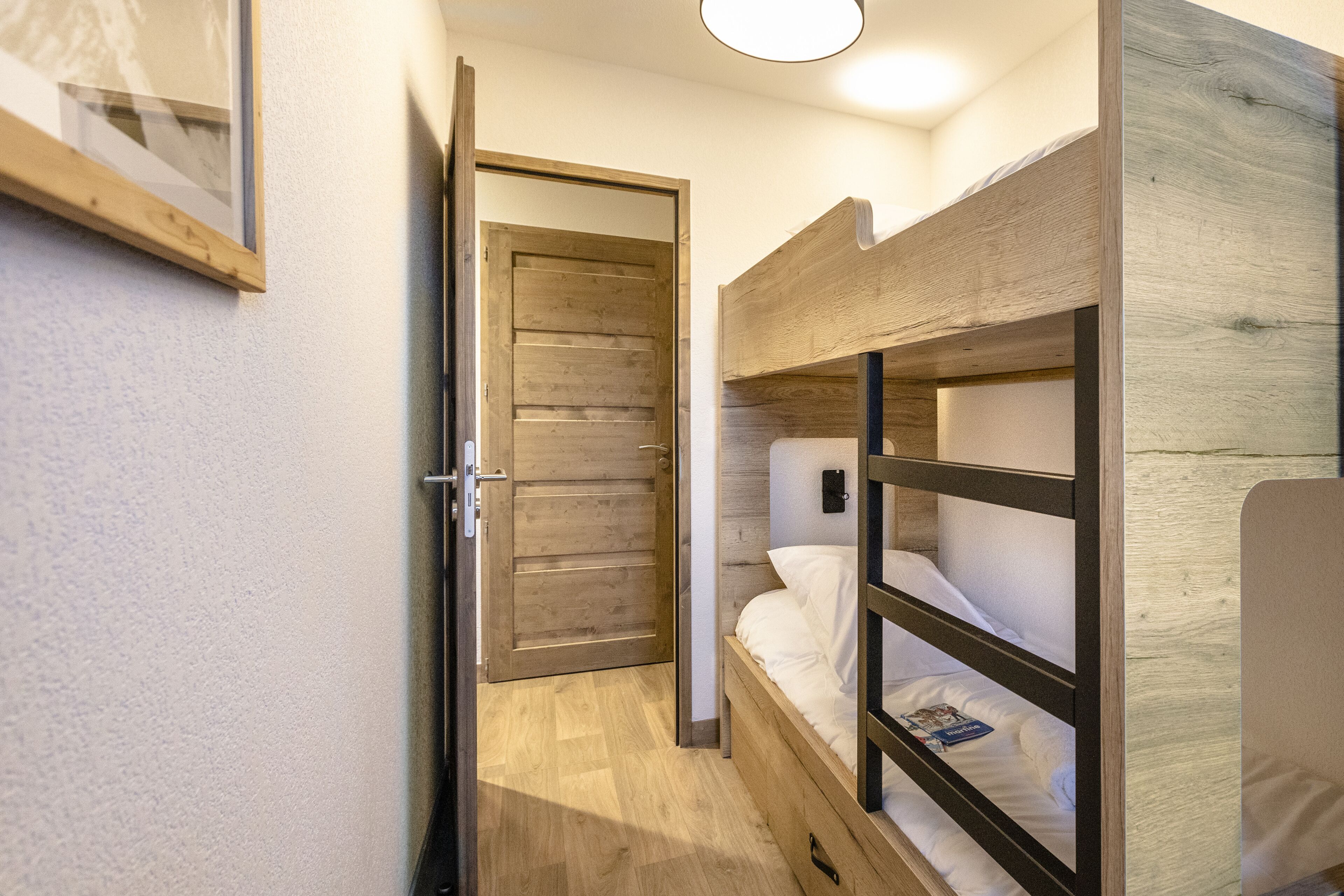Una habitación con literas, una puerta de madera y un cuadro en la pared.