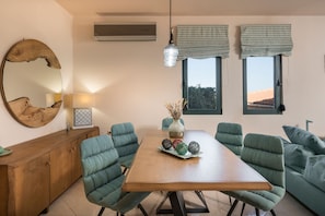 A dining area with a wooden table, green upholstered chairs, a decorative vase, and a large mirror on the wall. - Antonia Blue Villa (Chania)