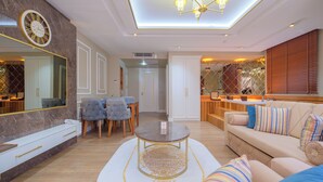 A modern living room with a sofa, a round coffee table, and a dining area with chairs and a table.
