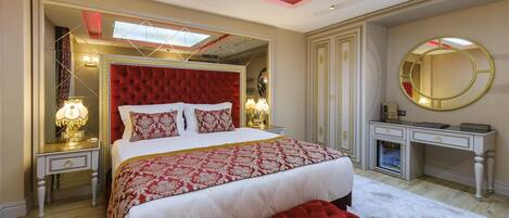 Een hotelkamer met een groot bed, een kaptafel met spiegel en een rode stoffen bank.