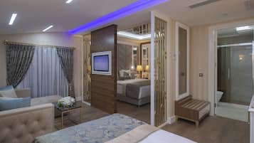 Una habitación de hotel moderna con una cama, una zona de estar, un televisor y un baño con ducha e inodoro.