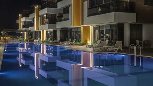 A modern hotel with a pool area, multiple balconies, and lounge chairs.