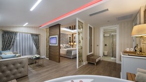 A modern living room with a large white bathtub, a sofa, and a TV.