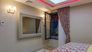 A bedroom with a large bed, a mirror, a window with curtains, and a skylight.
