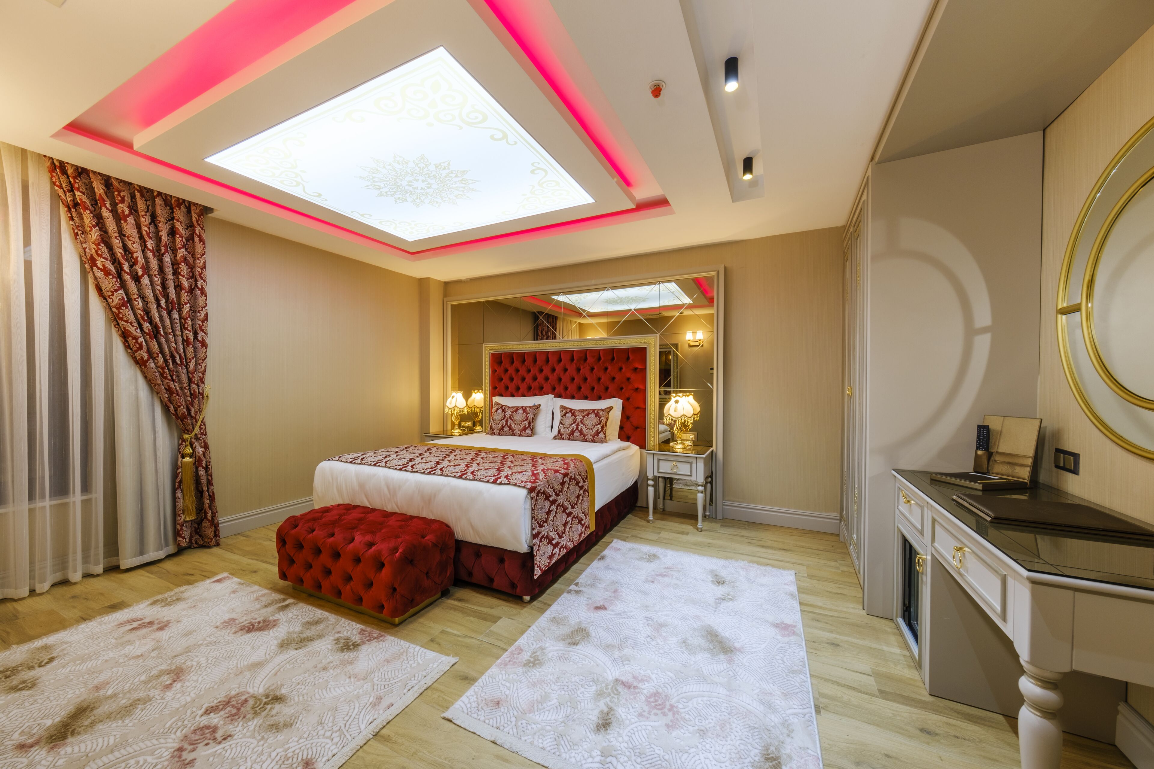 A bedroom with a bed, a desk, a mirror, and a skylight.
