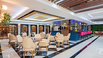 A modern hotel lobby with a bar area, seating arrangements, and a green wall.
