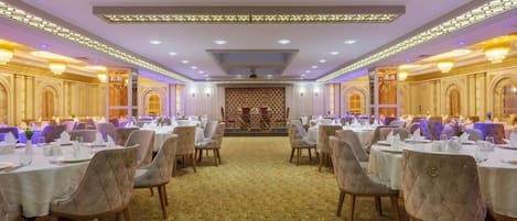Une salle de banquet avec des tables rondes et des chaises, une moquette à motifs et un plafond décoratif.