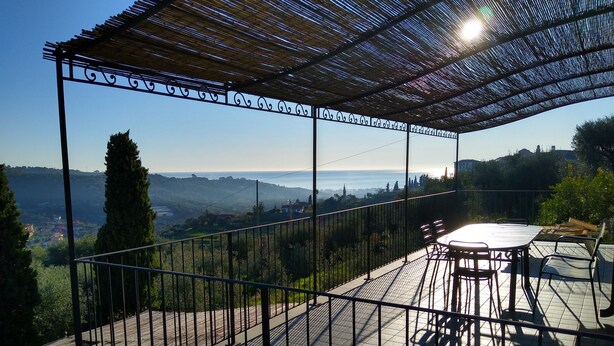 Ein überdachter Außenbereich mit Tisch und Stühlen, der auf eine reizvolle Landschaft blickt.