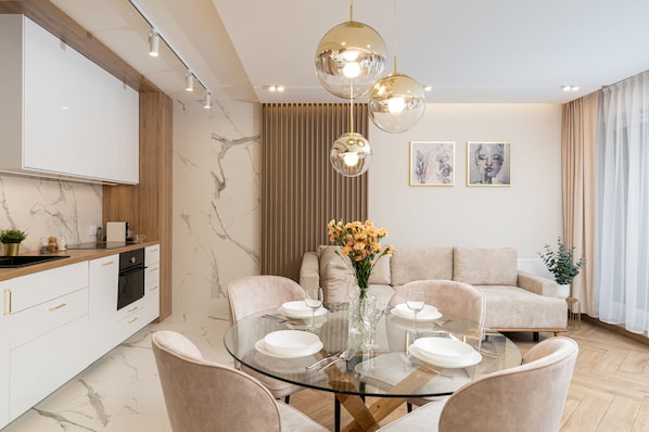 A modern dining area with a glass table, beige chairs, and a vase of flowers.