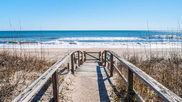 A wooden boardwalk leading to a beach with waves crashing onto the shore.